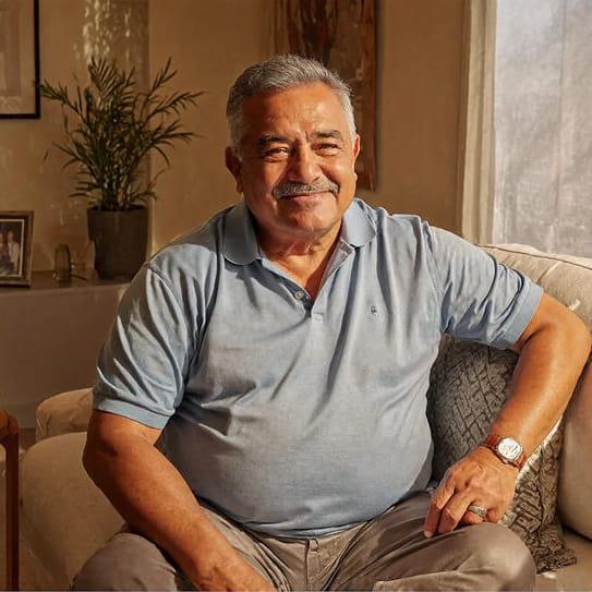 Smiling older man sitting on a sofa in a cozy living room with natural light
