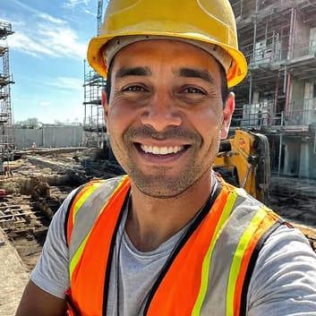 Smiling construction worker in safety vest and hard hat at an outdoor building site
